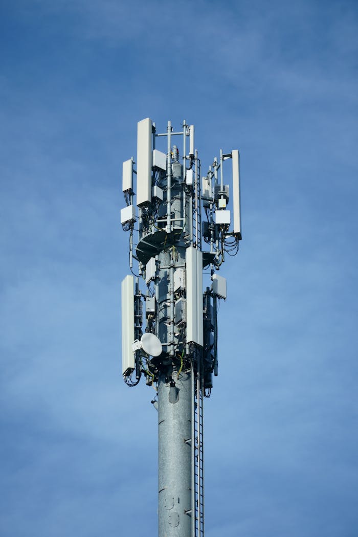 Telecommunication transmission tower with multiple antennas against a clear blue sky, showcasing modern connectivity technology.